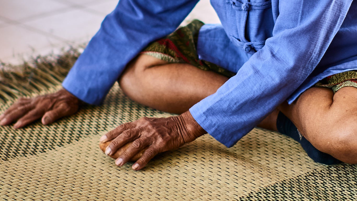 Woman in blue shirt working on a woven mat
